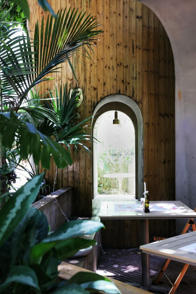 Charming cafe interior with arched window, lush plants, and wooden decor. Perfect for relaxing.
